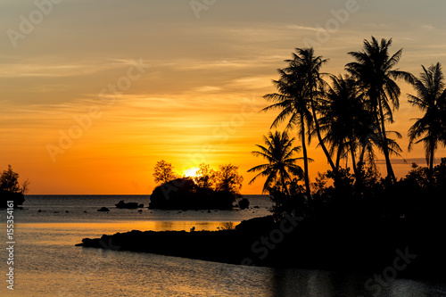 The sun setting behind small islands off of the small village of Agat on the  tropical island of Guam