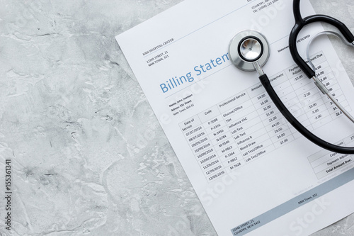 medical treatmant billing statement with stethoscope on stone background top view mockup photo