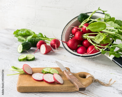 Young radishes and fresh cucumber slices on the kitchen table