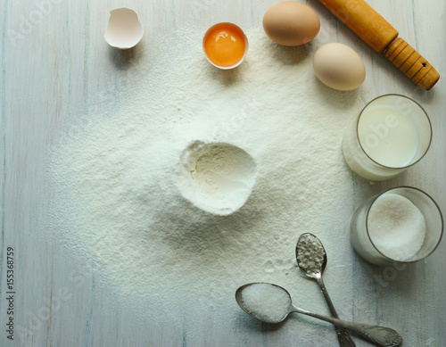 Eggs, flour, milk, sugar, on a white wooden table. photo