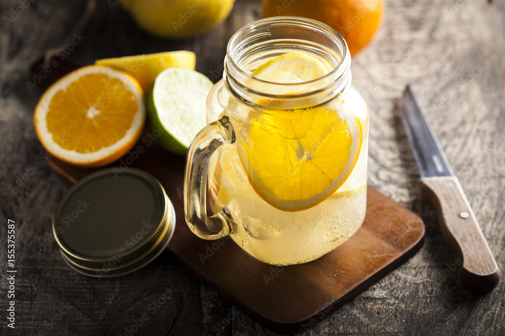 Lemonade in a mason jar with fruit slices on a wooden table Lemonade in a mason jar with fruit slices on a wooden table