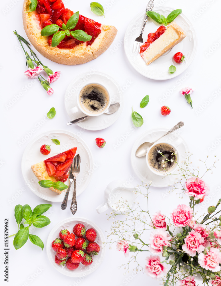 Flat lay with coffee, delicious homemade strawberry cheesecake and flowers over white. Top view.
