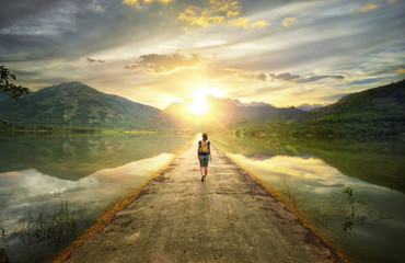 Hipster walking along the road to the mountains.