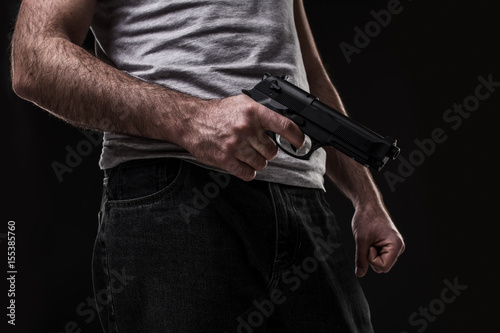 Killer with gun on black background at the studio