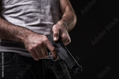 Killer with gun on black background at the studio