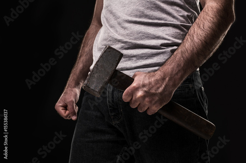 Male offender with a big hammer. On black background at the studio