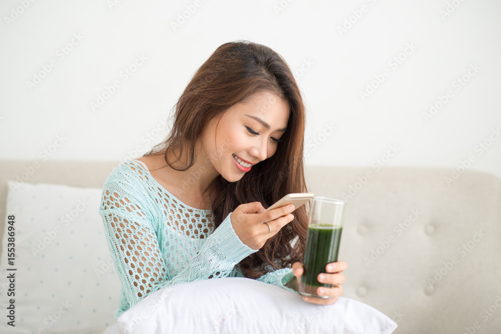 Asian woman using smartphone sitting on couch Asian woman using smartphone sitting on couch