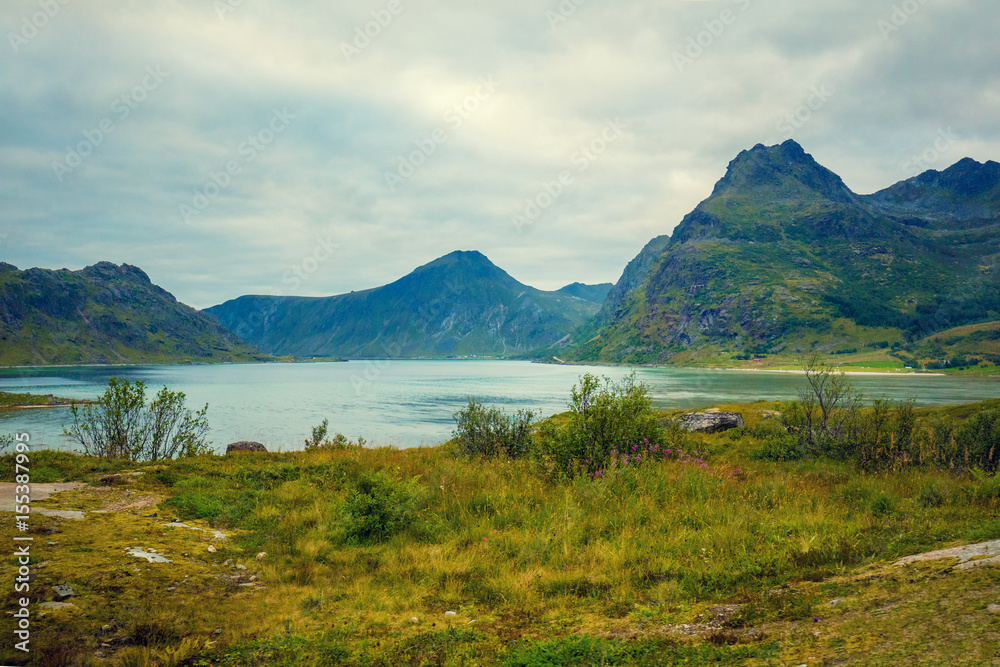 Mountain landscape with cloudy sky. Beautiful nature Norway. Lofoten islands. View at a fjord. 