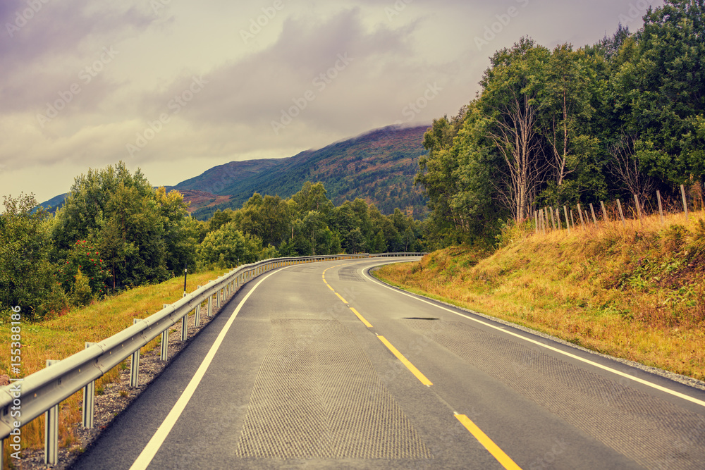 Driving a car on the mountain road. Road among mountains with the dramatic stormy cloudy sky. Beautiful nature Norway. Driving a car on the mountain road. Road among mountains with the dramatic stormy cloudy sky. Beautiful nature Norway.