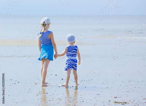 Two sister in striped clothes on the seashore looking into the distance