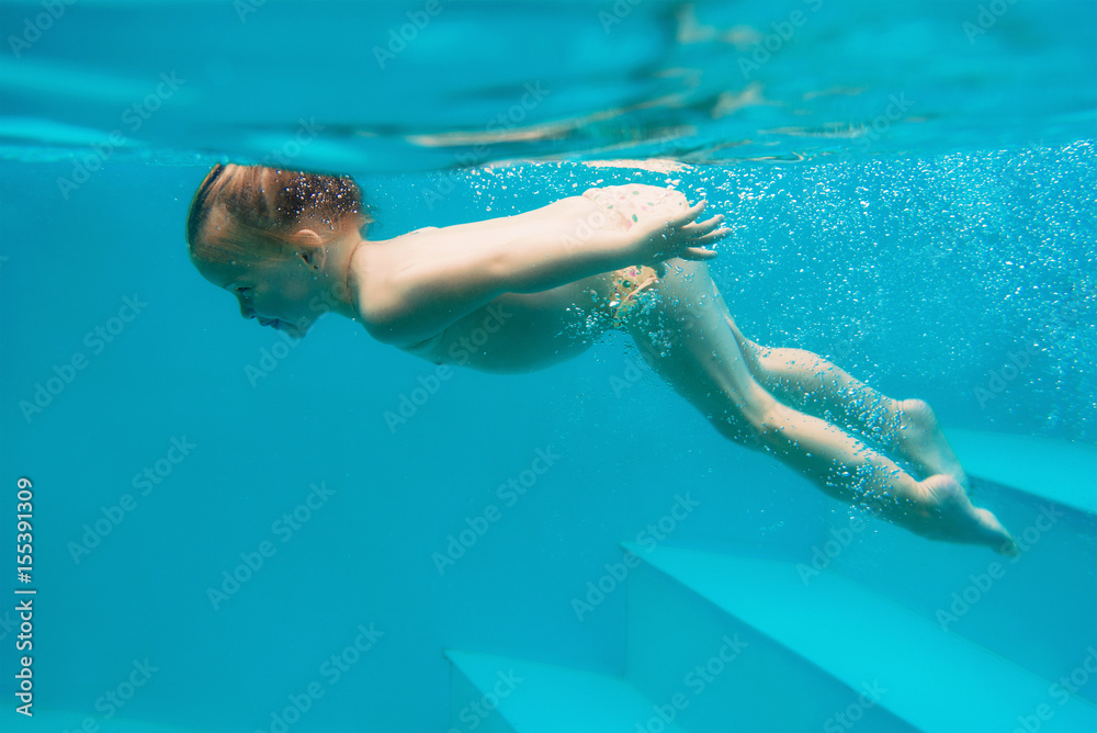Young girl diving underwater in the swimming pool