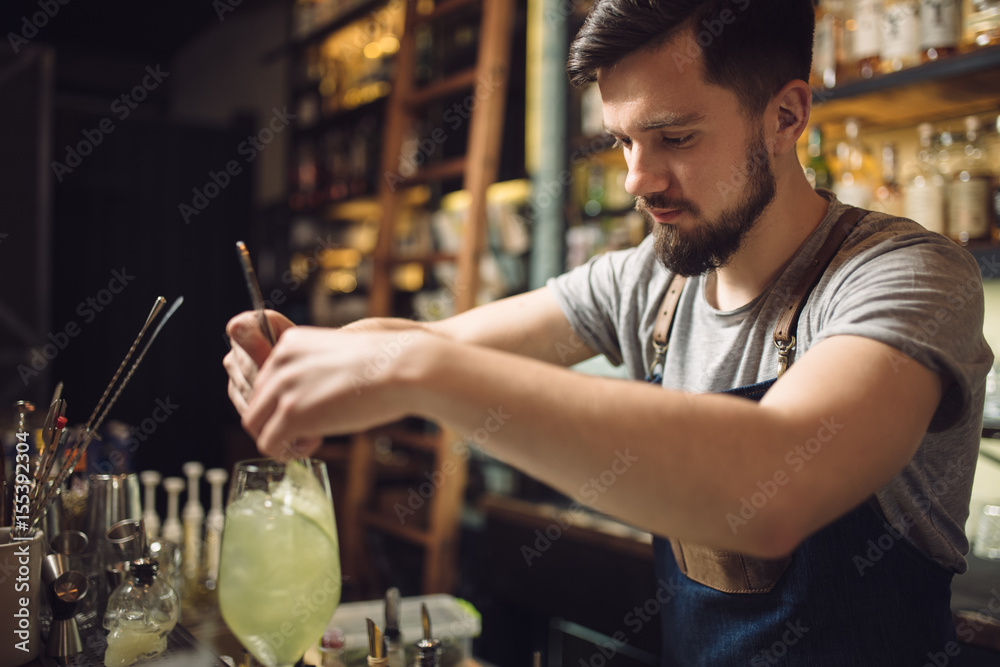 Young male bartender preparing an alcohol cocktail