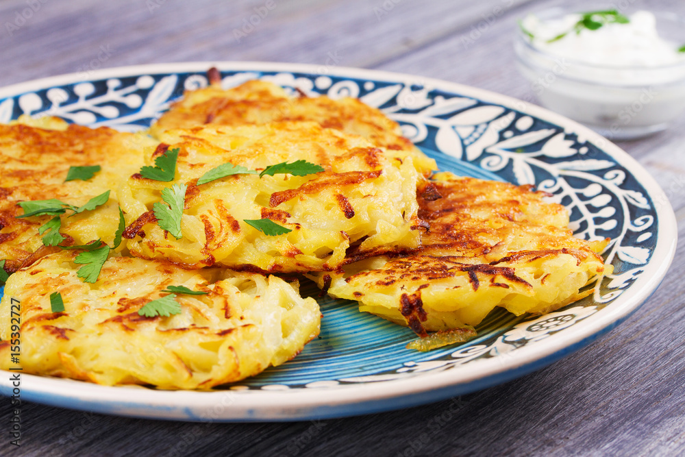 Potato Pancakes With Yogurt Sauce. Vegetable fritters. Latkes on blue plate Potato Pancakes With Yogurt Sauce. Vegetable fritters. Latkes on blue plate