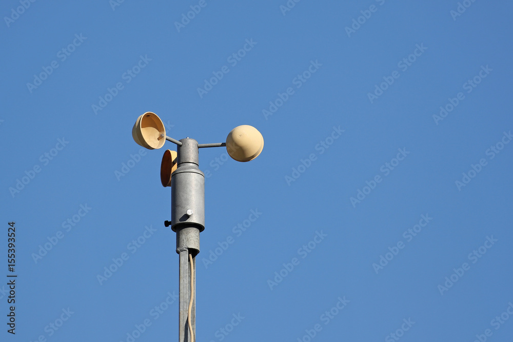 Anemometer measuring wind speed with small cups pushed by the wind like a small windmill against clear blue skies Anemometer measuring wind speed with small cups pushed by the wind like a small windmill against clear blue skies