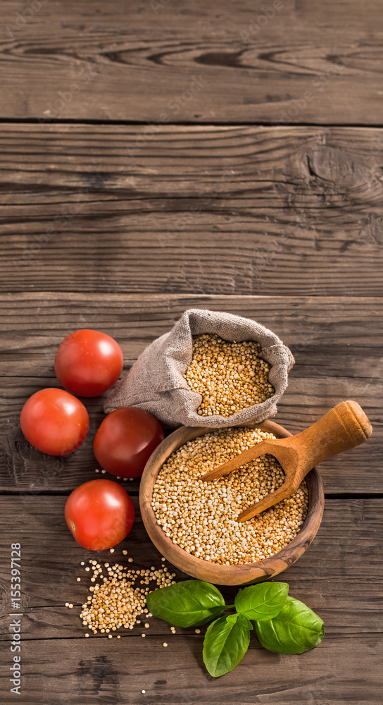 Uncooked quinoa with tomatoes and basil on old wooden background Uncooked quinoa with tomatoes and basil on old wooden background