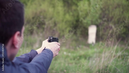 Male hand holding gun, reloading it and shooting from it on a field shooting