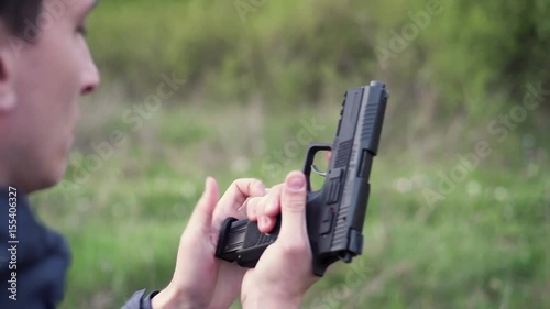 Male hand holding gun, reloading it and shooting from it on a field shooting
