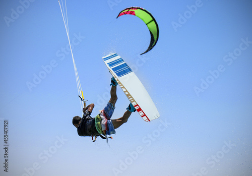 Recreational water sports: kitesurfing. Kiteboarding sportsman jumping high in the sky on windy day. Extreme sports action with wind and water. Healthy active lifestyle.Summer fun adventure and hobby.