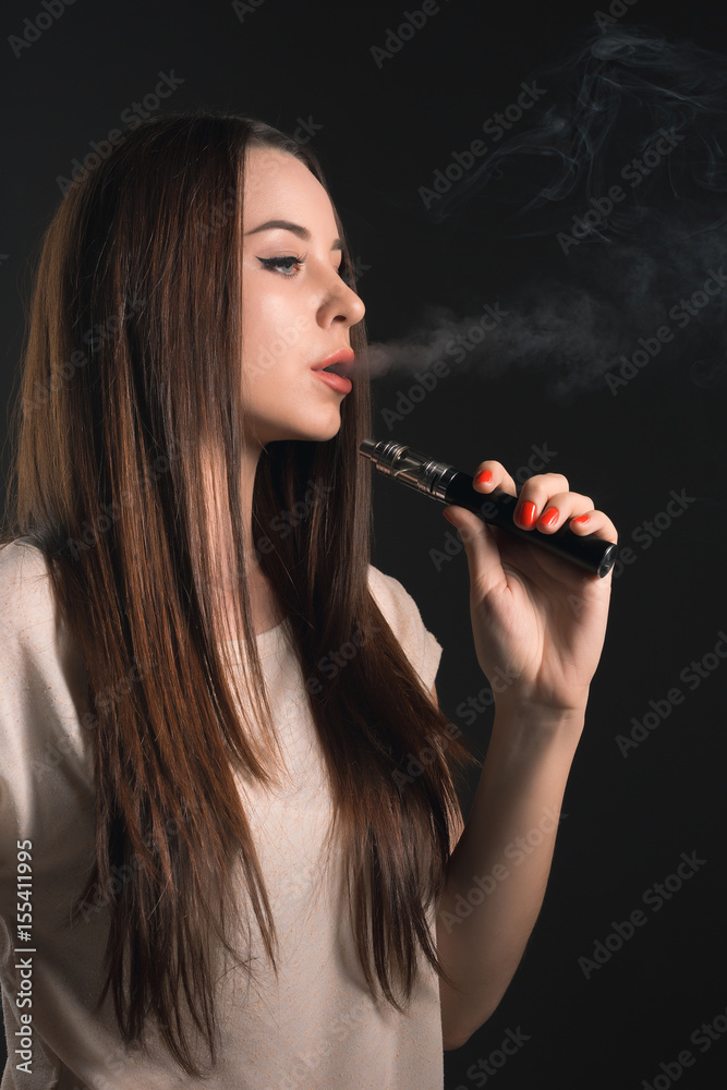 Obraz premium The face of vaping young woman at black studio