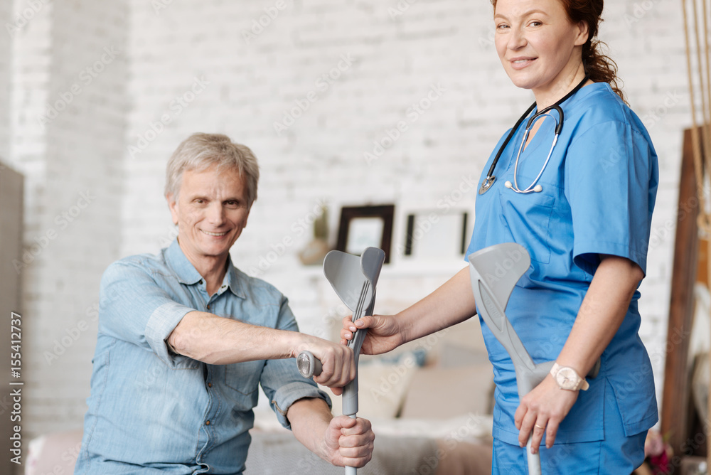 Obraz premium Attentive diligent nurse brining her patient the crutches