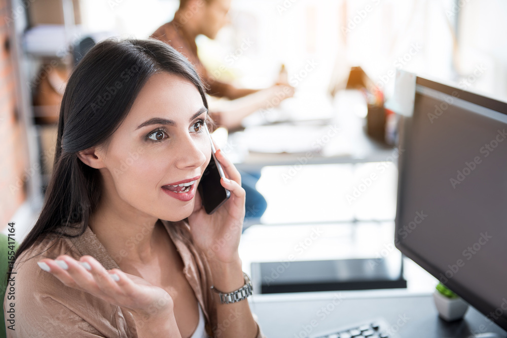 Astonished smiling female office worker keeping smartphone Astonished smiling female office worker keeping smartphone