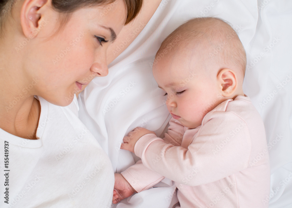 Young mother looking at her sleeping baby girl Young mother looking at her sleeping baby girl