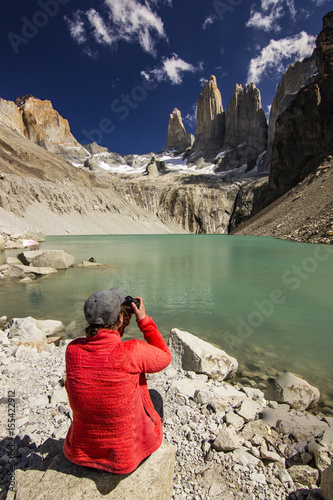 girl in red jacket sitting on the stone above lake in patagonia