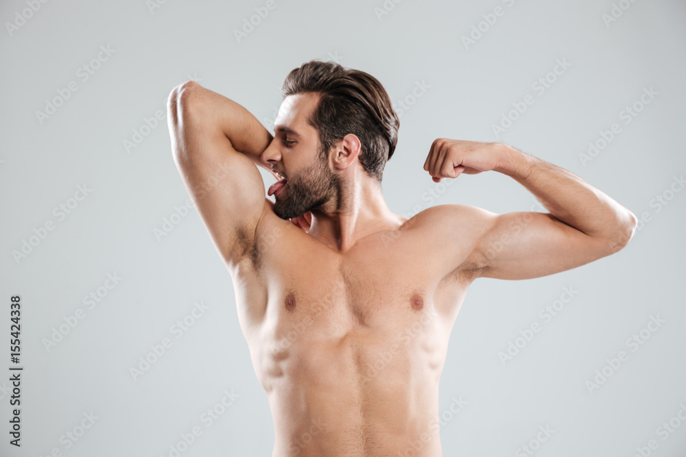 Fototapeta premium Handsome young naked man showing and kissing his biceps