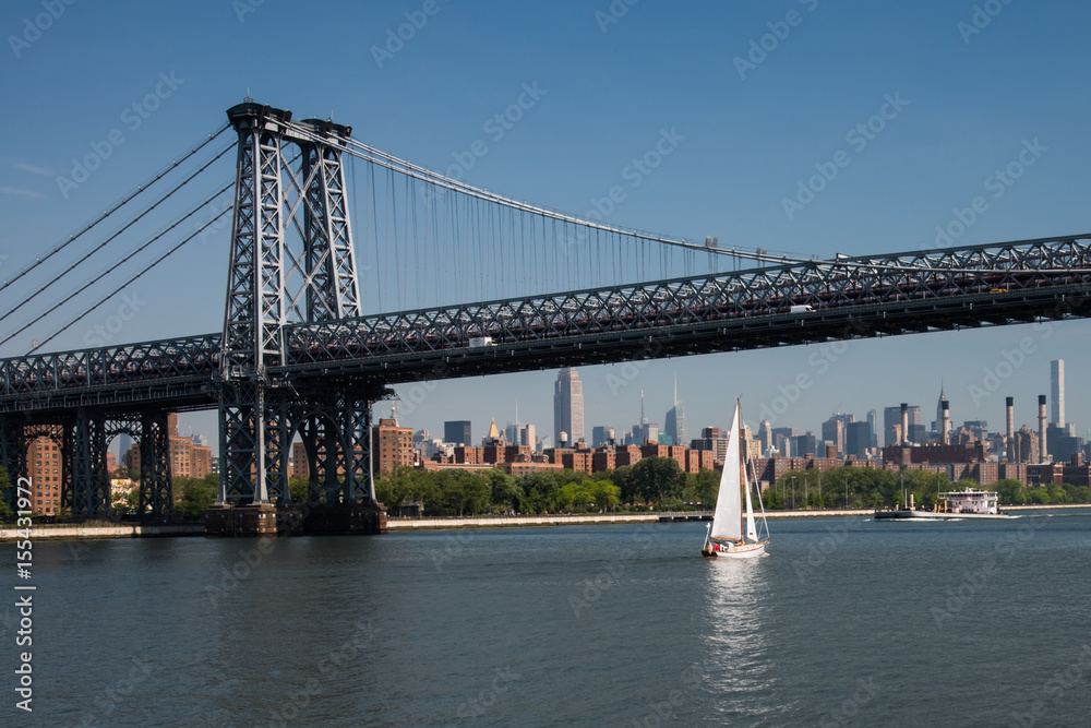 Fototapeta premium Żaglówka przepływa pod mostem Williamsburg łączącym Manhattan z Brooklynem