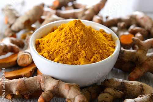 Turmeric powder in white cup on wooden floor