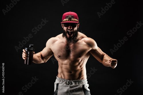 Foto Bodybuilder criant, un shaker de protéine à la main