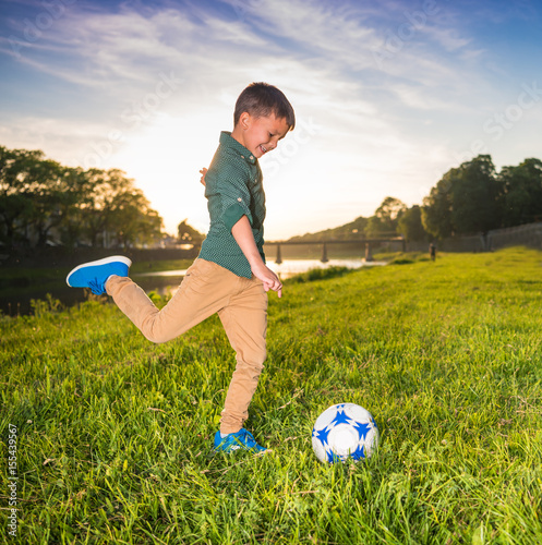  Happy smiling boy kicking ball in the field