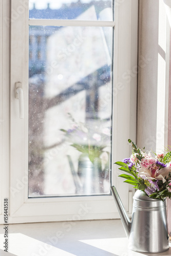 vertical still life flowers in watering can in sunlight