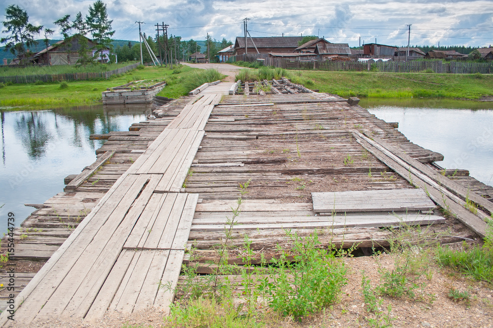 Old ruined wooden bridge across the river. Rural broken crossing of the Creek. Rural landscape