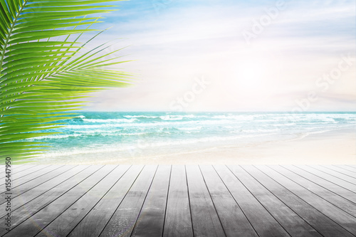 Empty wooden table and palm leaves with party on beach blurred background. Concept Summer, Beach, Sea, Relax, Party.