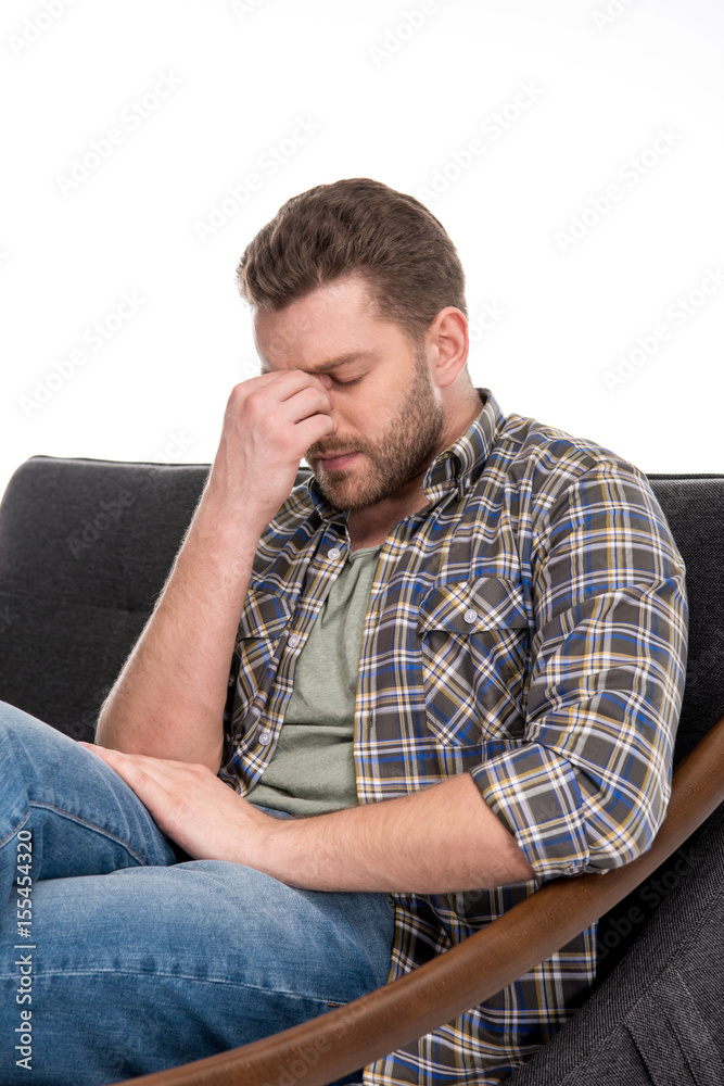 Upset bearded man sitting on sofa isolated on white Upset bearded man sitting on sofa isolated on white