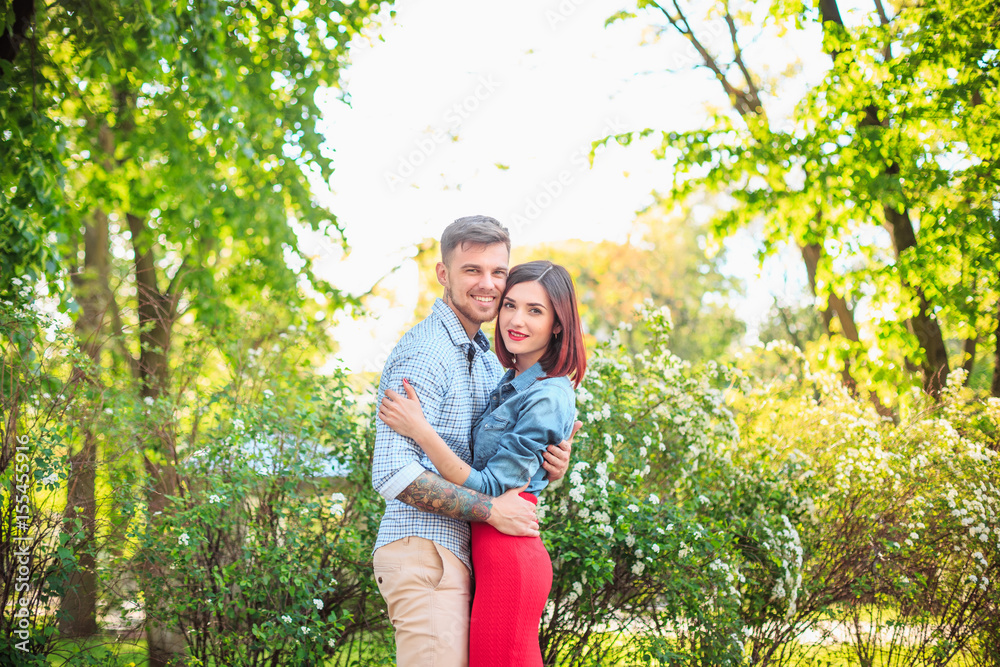 Happy young couple at park standing and laughing on the bright sunny day Happy young couple at park standing and laughing on the bright sunny day