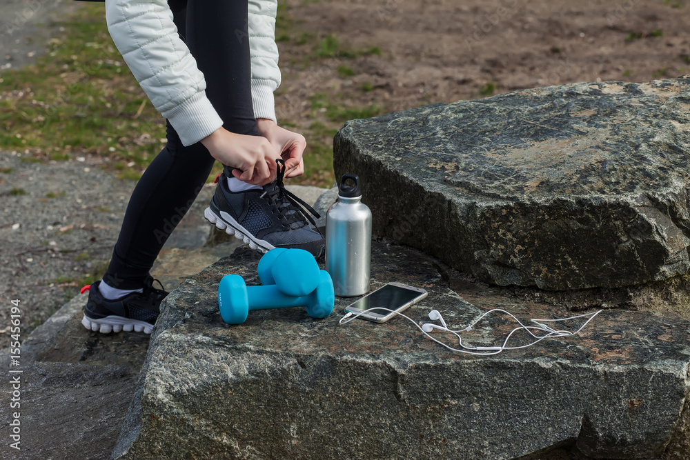 Woman fix shoelaces, equipment for fitness, phone and headphones Woman fix shoelaces, equipment for fitness, phone and headphones