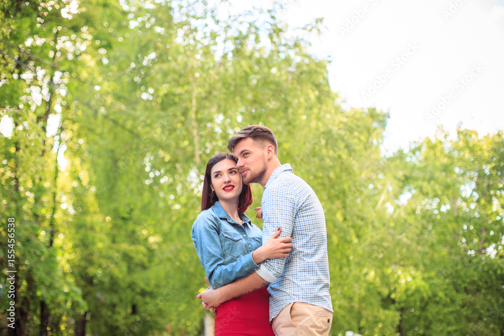 Happy young couple at park standing and laughing on the bright sunny day Happy young couple at park standing and laughing on the bright sunny day
