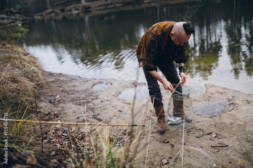 Young fisherman catches a fish on lake © shunevich