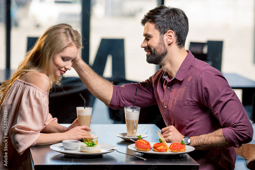 side view of couple in love having lunch in restaurant together side view of couple in love having lunch in restaurant together