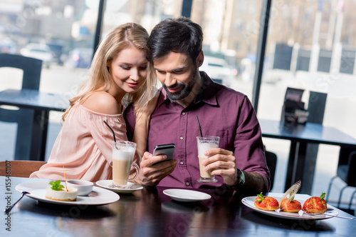 romantic couple in love using smartphone on coffee break in restaurant