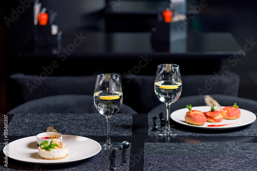 close up view of tasty desserts and glasses of water on table in restaurant