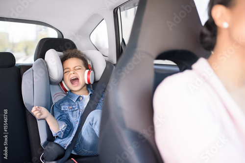 little african american girl listening music with mother sitting in car