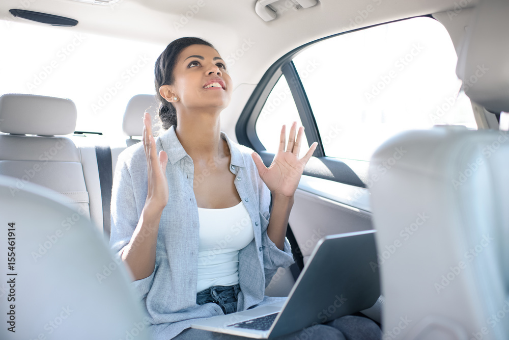angry african american woman working with laptop in taxi