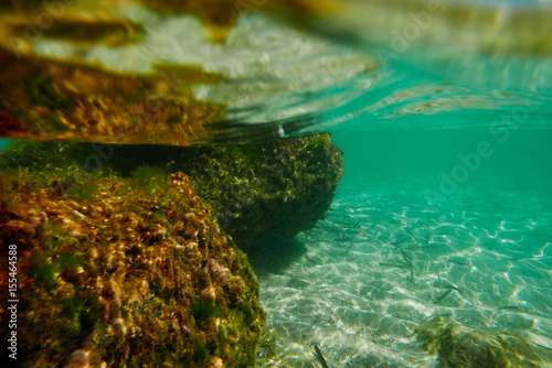 Underwater scenery in shallow sea waters, with big stones and sand.