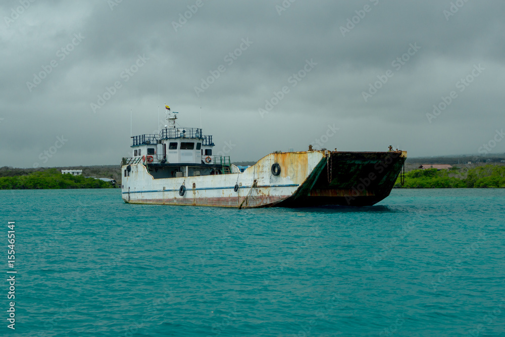 Old Fishing Boat sailing in a beautiful magenta waters in Galapagos in a cloudy day