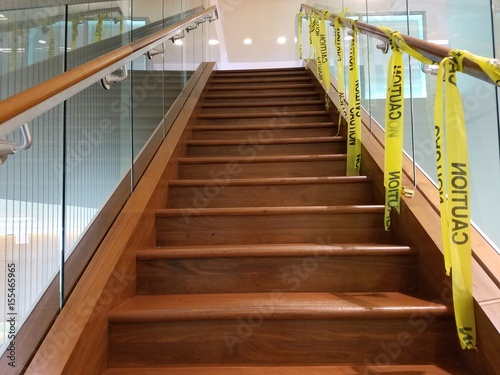 wood and glass staircase with caution tape