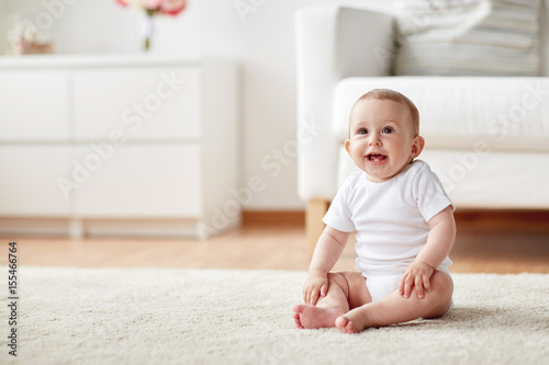 happy baby boy or girl sitting on floor at home