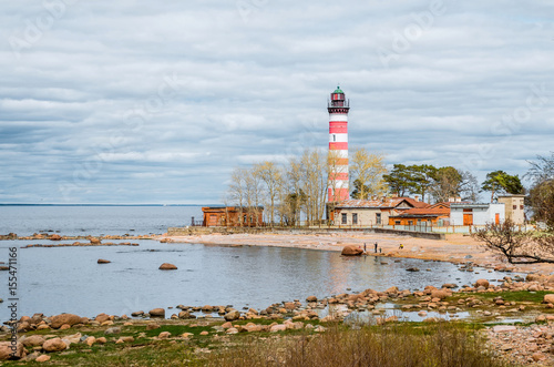 View of the cape on the coast with the old lighthouse in red and white stripes.
